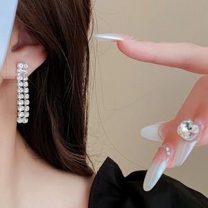 Close-up of elegant silver tassel earrings with sparkling rhinestones on a female model