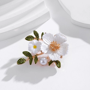 Broche fleurie avec marguerite, perle et feuilles sur fond blanc minimaliste