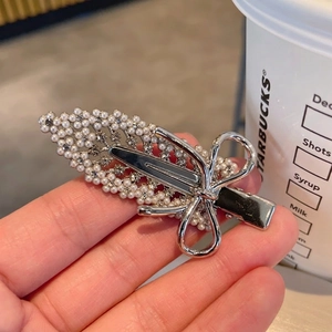 Close-up of silver metal bow hair clip with embedded pearls and sparkling rhinestones