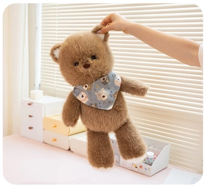 Close-up of a soft brown plush bear toy with a blue scarf in a warm home setting