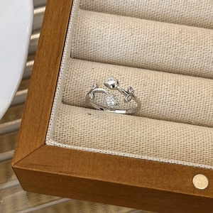 Macro shot of silver tulip open ring featuring micro-pave crystals on wooden jewelry stand