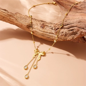 Collier noeud doré élégant avec glands et zircons goutte d'eau sur branche de bois