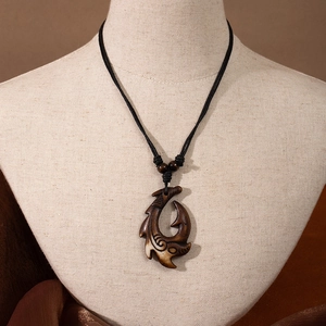 Maori style resin fish hook pendant necklace on a jewelry bust with brown cord