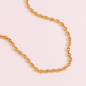 Macro shot of 18K gold plated oval bead chain necklace with polished metallic finish