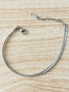 Sleek silver stainless steel Cuban chain bracelet with lobster clasp on wooden background