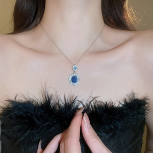Close-up of elegant silver necklace featuring a deep blue oval sapphire pendant and diamonds