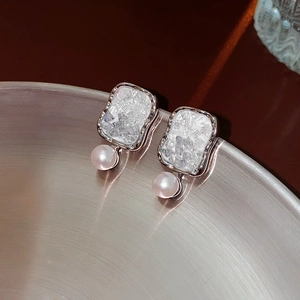Macro shot of silver crystal butterfly flower earrings with pink pearl on metal rim
