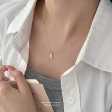 Close-up of a delicate S925 sterling silver gold crescent moon necklace on a female model