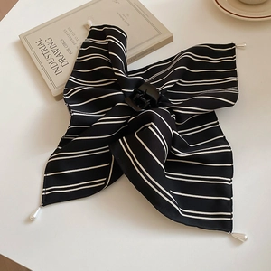 Détail d'une pince à cheveux en tissu rayé noir et blanc avec des perles élégantes