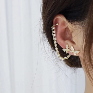 Detail of crystal butterfly ear cuff earring with white pearls on a gold chain