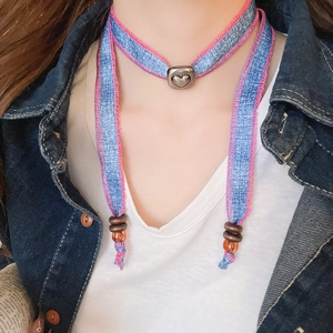 Detail of denim heart pendant necklace with pink stitching and brown bead accessory