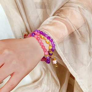 Detail of beaded floral bracelet with purple and pink crystals and gold flower charms