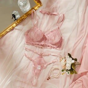 Pink lace lingerie set with heart metal detail and strappy thong on a soft silk background