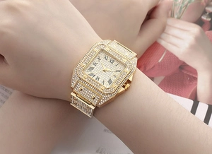 Close-up of a gold square watch with crystal embellishments and Roman numerals