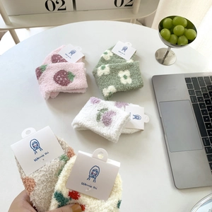Close-up of cozy coral fleece socks with cute cartoon patterns on a white table