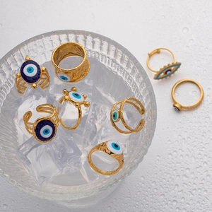 Detail of vintage gold evil eye rings with blue enamel on textured ice and water background