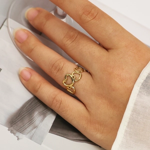 Detail of a minimalist 18k gold plated open ring with heart shapes worn by a model