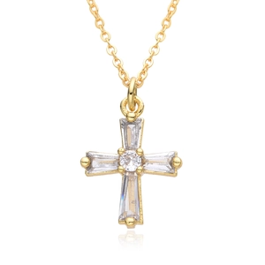 Detailed view of a gold cross pendant necklace featuring cubic zirconia on white mirror surface