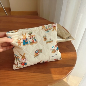 Close-up of quilted cotton makeup bag featuring cute rabbit garden print and logo tag