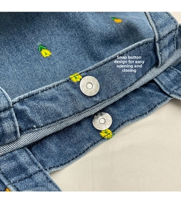 Detail eines silbernen Magnetverschlusses an der Jeans-Tasche mit Stickerei