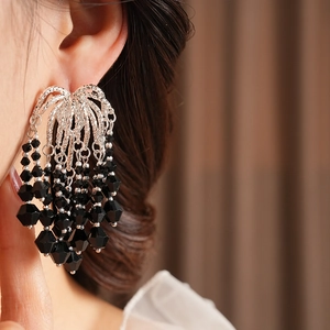 Detail of silver fan-shaped earrings with black glass beads fringe on a model
