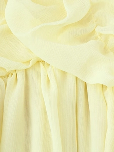 Close-up of light yellow pleated chiffon fabric with soft texture and refined grain