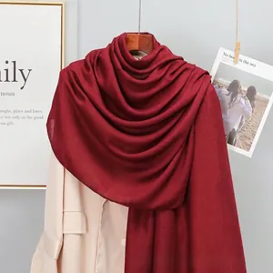 Close-up of lightweight burgundy cotton linen scarf draped over a beige blazer jacket