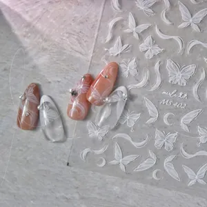 Détail de stickers à ongles papillon blanc et lune sur une manucure perlée élégante