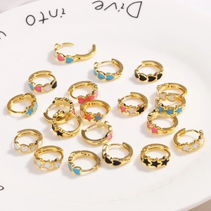 Golden hoop earrings with colorful enamel hearts and stars scattered in a white tray
