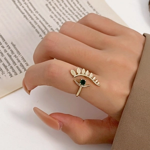 Detailed close-up of a gold-plated evil eye ring featuring a green zircon center stone
