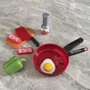 Detailed view of an 8-piece plastic toy cooking set including pan, spatula and food items