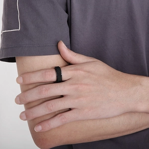 Close-up of black rotatable stainless steel ring with mesh texture on a male finger