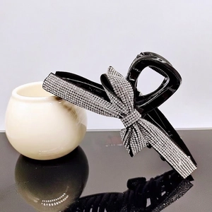 Detailed view of a black hair claw clip featuring a rhinestone-studded bow design