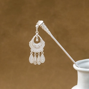 Detailed view of silver hollowed hair stick with crescent motif and water drop pendants