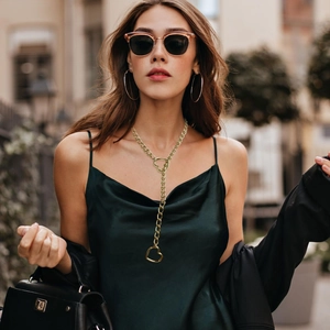 Close-up of golden heart pendant necklace on a model with a green silk dress