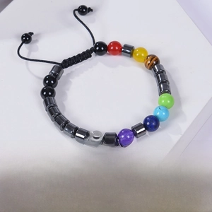 Close-up of 7 Chakra gemstone beaded bracelet with adjustable woven cord on white stand