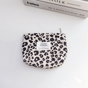 Detail of leopard print canvas makeup bag with metallic zipper and lifestyle props
