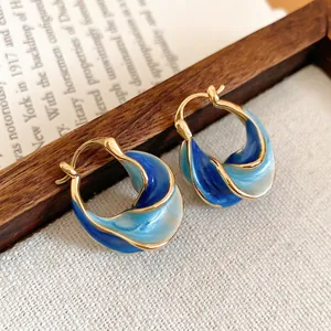 Elegant twisted hoop earrings with blue gradient enamel in a warm gold finish
