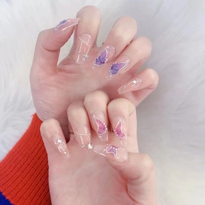 Detail of handmade press-on nails with butterfly motifs, pearls, and silver chains