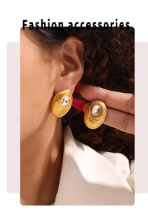 Detailed view of gold oval earrings with spiral texture and crystal stud on model
