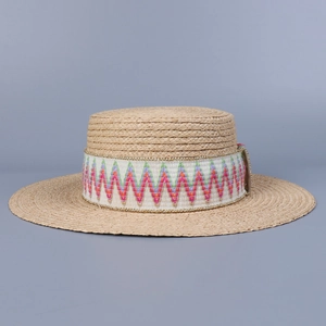 Detail of bohemian raffia boater hat with colorful geometric woven ribbon trim