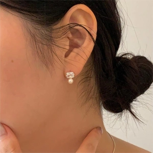 Close-up of elegant 925 silver stud earring with square crystal and white pearl on ear