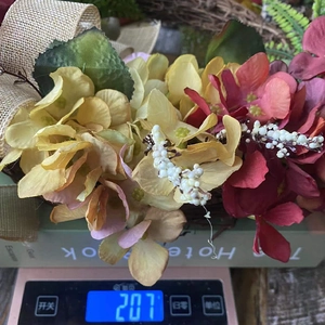 Detailed view of artificial floral wreath weight measurement at 207g on digital scale