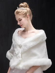 Detailed view of white bridal faux fur shawl featuring a sparkling rhinestone brooch clasp