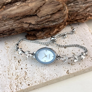 Macro detail of silver oval quartz watch with leaf-shaped crystal accents on stone