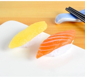Macro shot of realistic PVC salmon and egg sushi models on a white plate with chopsticks