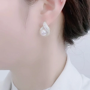 Detail of waterdrop pearl earrings with pavé zircons on a model for a luxury look