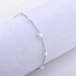 Vue macro détaillée de perles blanches de 4mm sur un bracelet en acier inoxydable argenté