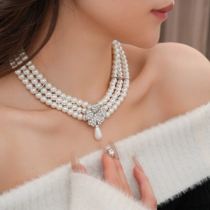 Close-up of multi-layer pearl necklace with a sparkling floral diamond pendant detail
