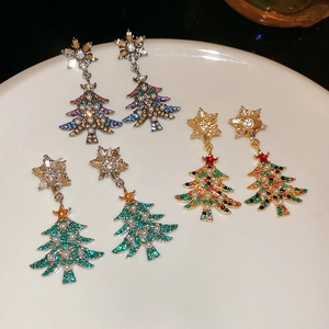 Detailed view of rhinestone Christmas tree earrings with pearls on white plate